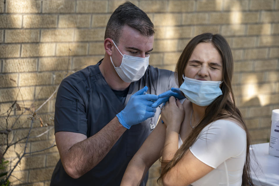 Amanda De Lara, 16, right, winces as she receives the first dose of the Pfizer COVID-19 vaccine from National Guard Specialist Noah Vulpi during a vaccination clinic held by the National Guard Thursday, May 27, 2021 in Odessa, Texas. (Eli Hartman/Odessa American via AP)