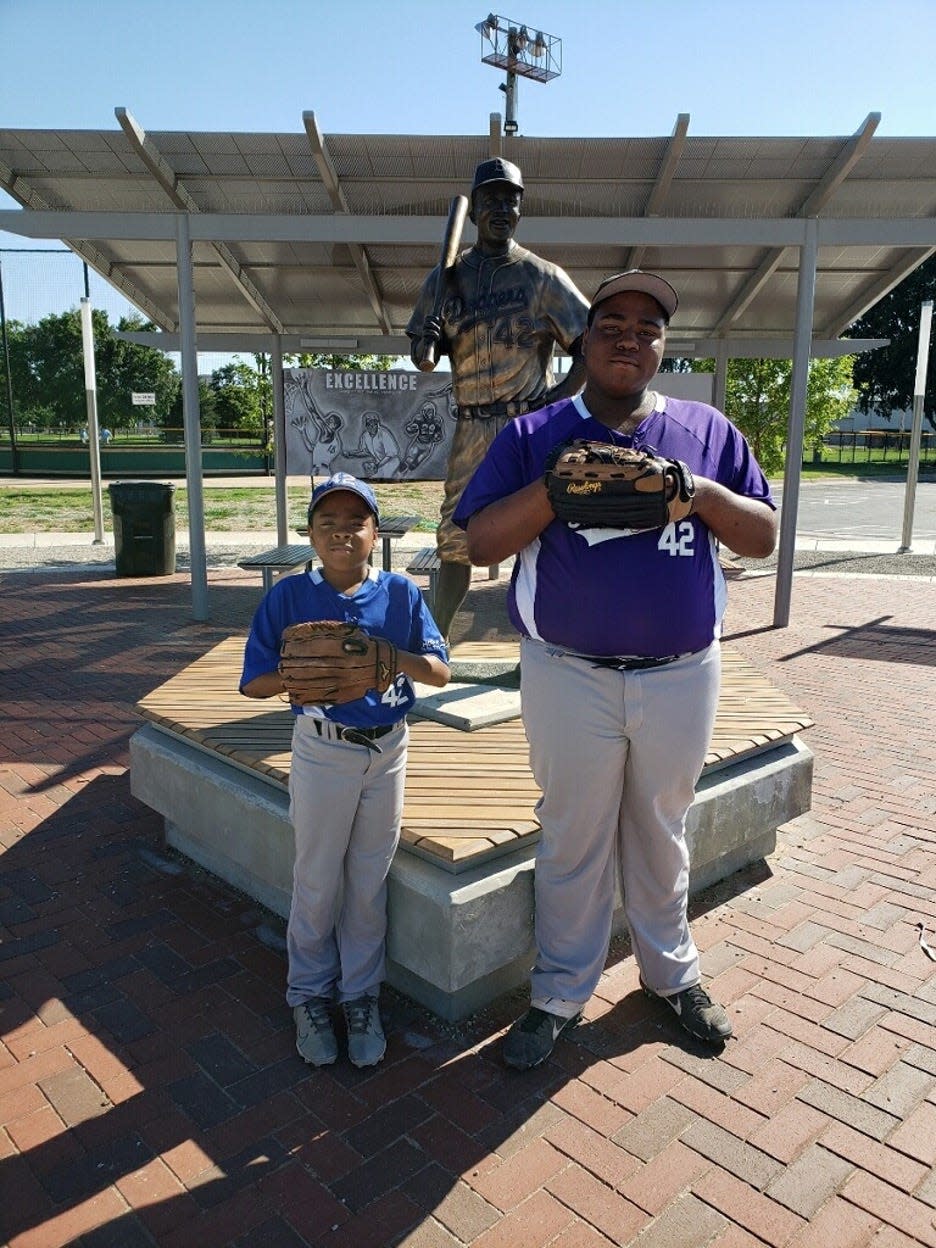 Taryn Redd and his younger brother, Trason Redd, stand in front of the Jackie Robinson statue at McAdams Park in Wichita, Kansas before the statue was stolen.