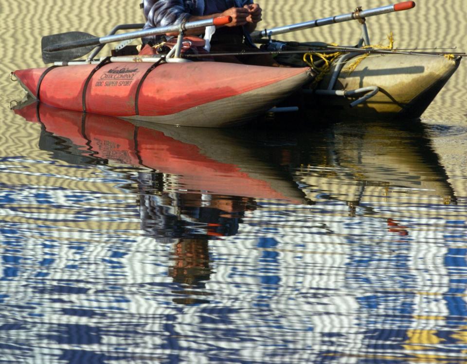 A fisherman's reflection is broken up by shimmering waters as he fishes from a float tube along the downtown waterfront in Stockton.