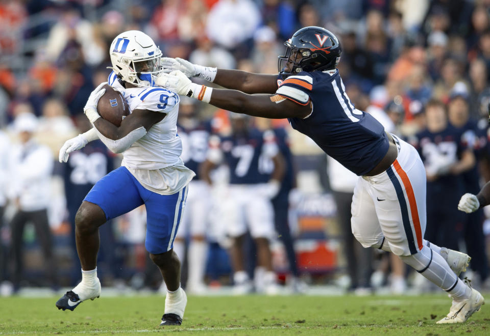 Virginia defensive tackle Michael Diatta, right, is called for face masking as he tries to bring down Duke running back Jaquez Moore (9) during the first half of an NCAA college football game Saturday, Nov. 18, 2023, in Charlottesville, Va. (AP Photo/Mike Caudill)