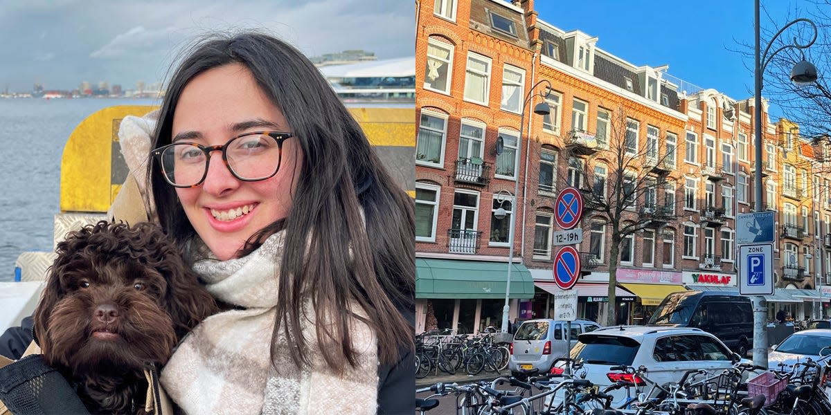 Author holding dog by water. Buildings of neighborhood in Amsterdam.