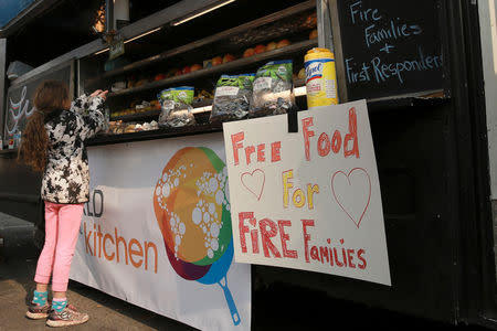 Miruia Eubanks, 9, grabs some free food from a food truck in Chico, California, U.S. November 20, 2018. REUTERS/Elijah Nouvelage