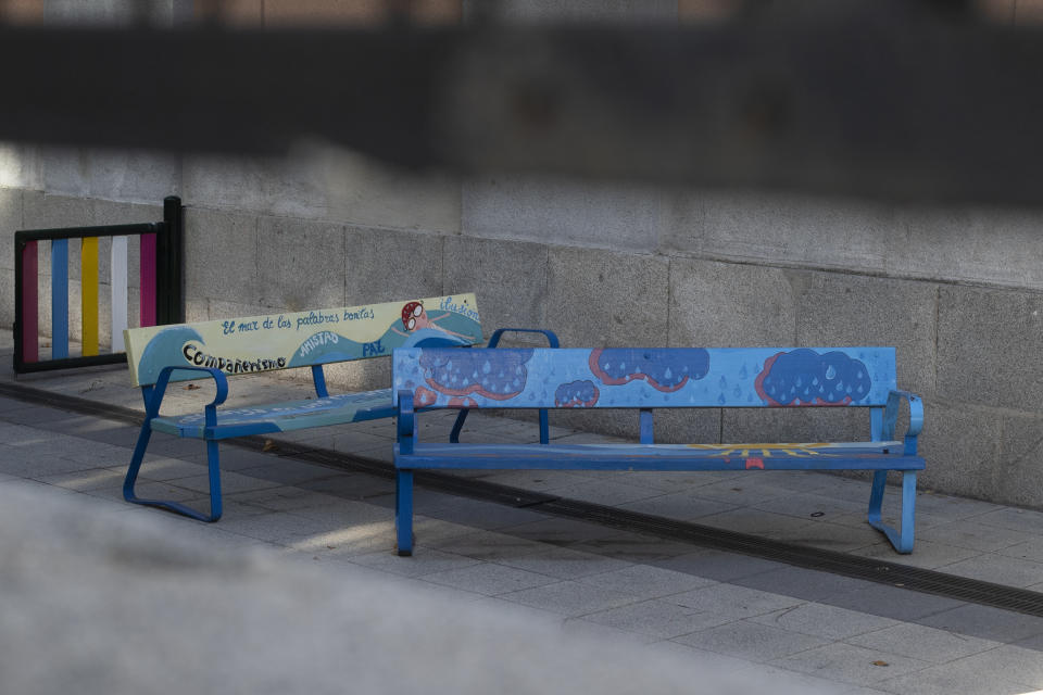 Children's painted benches with messages written on them sit outside a school building in Madrid, Spain, Tuesday, Aug. 25, 2020. Despite a spike in coronavirus infections, authorities in Europe are determined to send children back to school. Schools in the Spanish capital are scheduled to open on Sept. 4. (AP Photo/Paul White)