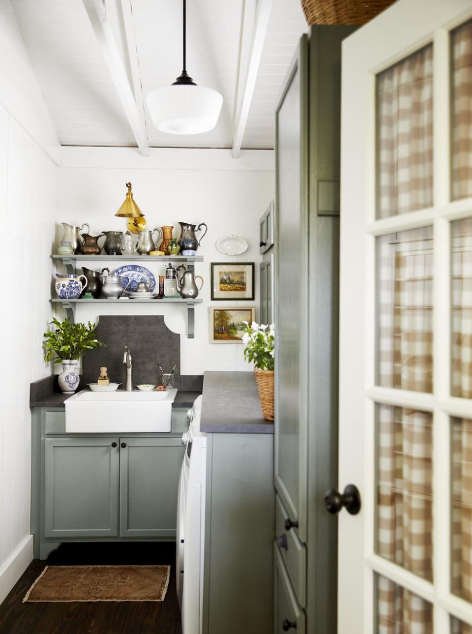 small laundry room with gray green cabinetry and slate sink