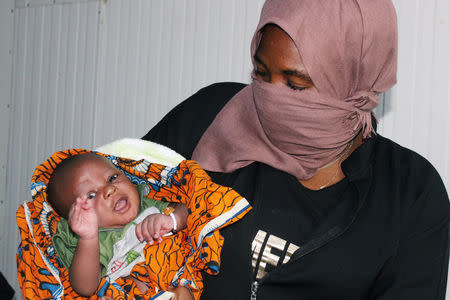 A migrant woman from Mali holds her child as she waits at Misrata airport before return to her country, in Misrata, Libya September 20, 2018. REUTERS/Ayman al-Sahili