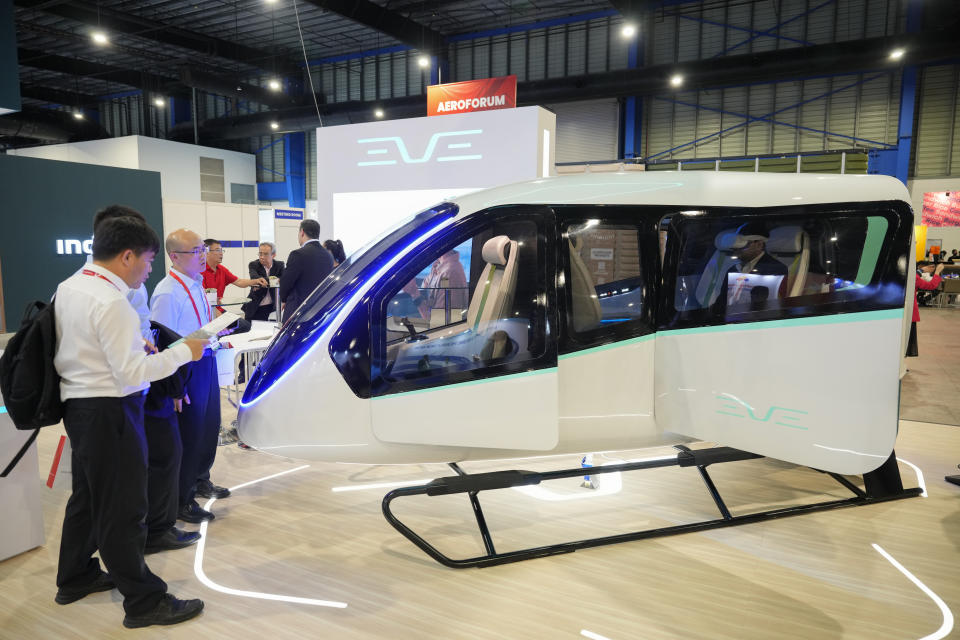 Visitors look at Brazilian firm Eve Air Mobility, a spin-off by third largest aircraft manufacturer Embraer, in Singapore, Thursday, Feb. 22, 2024. As the aviation sector seeks ways to make air travel less polluting and more sustainable, aerospace company Embraer and South Korean automaker Hyundai are among the companies betting on a new form of air travel, air taxis. (AP Photo/Vincent Thian)