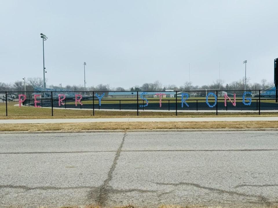 "Perry Strong" is spelled out using cups along the football field's fence across from the Perry High School following a shooting there on Jan. 4.