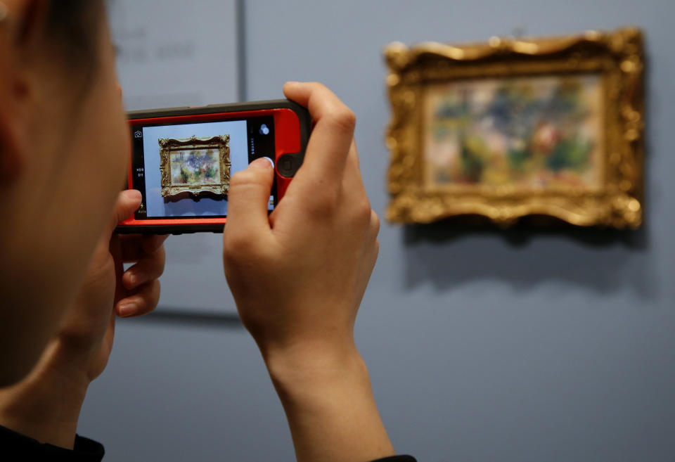 A woman photographs Pierre-Auguste Renoir's painting "On the Shore of the Seine" after a news conference at the Baltimore Museum of Art in Baltimore, Thursday, March 27, 2014, more than 60 years after it was stolen from the museum. The painting became the subject of a dramatic legal dispute after a Virginia woman claimed she bought it at a flea market for $7. A judge ultimately awarded ownership back to the Baltimore museum, and it is scheduled to go on public display March 30. (AP Photo/Patrick Semansky)