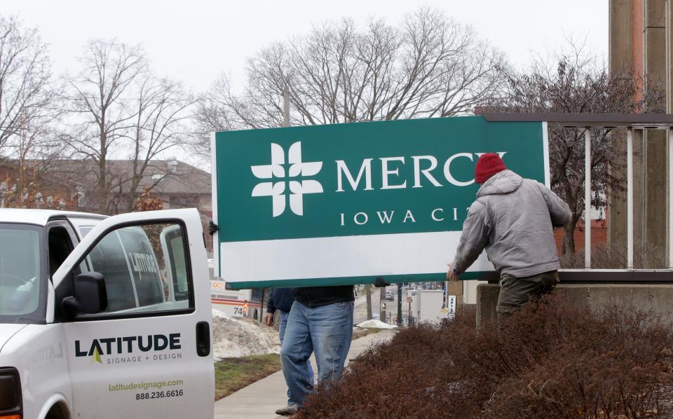 Latitude Signage & Design employees remove a Mercy Iowa City sign outside the hospital’s main entrance Wednesday, Jan. 31, 2024 in Iowa City, Iowa.