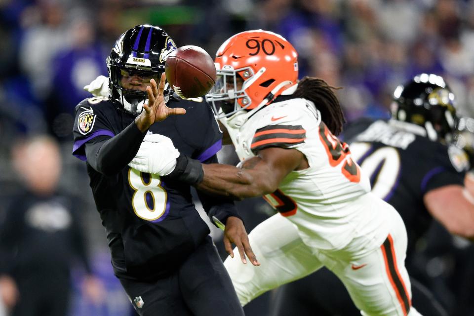 Baltimore Ravens quarterback Lamar Jackson (8) pitches the ball to running back Devonta Freeman, not visible, as Cleveland Browns defensive end Jadeveon Clowney (90) applies pressure during the first half of an NFL football game, Sunday, Nov. 28, 2021, in Baltimore. (AP Photo/Gail Burton)