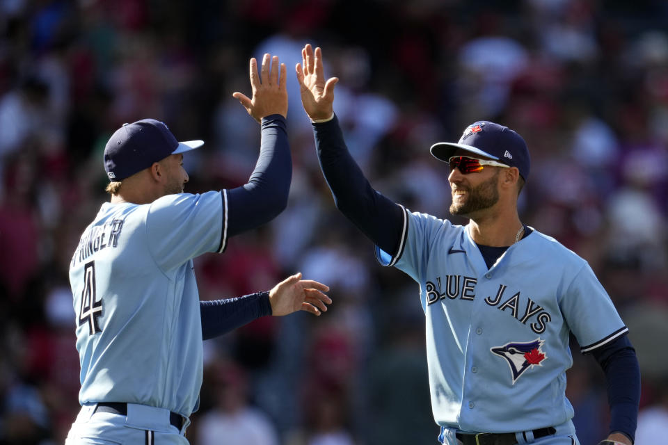 Toronto Blue Jays' Kevin Kiermaier, right, and George Springer (4) celebrate after a 12-11 win over the Los Angeles Angels during a baseball game Sunday, April 9, 2023, in Anaheim, Calif. (AP Photo/Marcio Jose Sanchez)