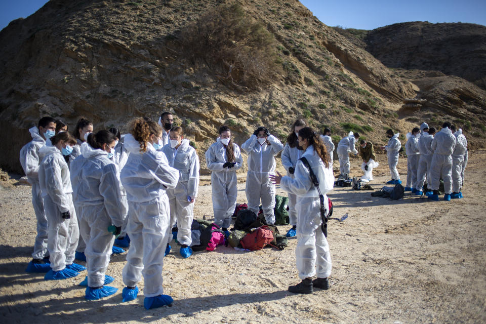 Israeli soldiers wearing protective suits listen to a briefing ahead of cleanup operations to remove tar from a beach after an oil spill in the Mediterranean Sea At Sharon Beach Nature Reserve, near Gaash, Israel, Monday, Feb. 22, 2021. (AP Photo/Ariel Schalit)