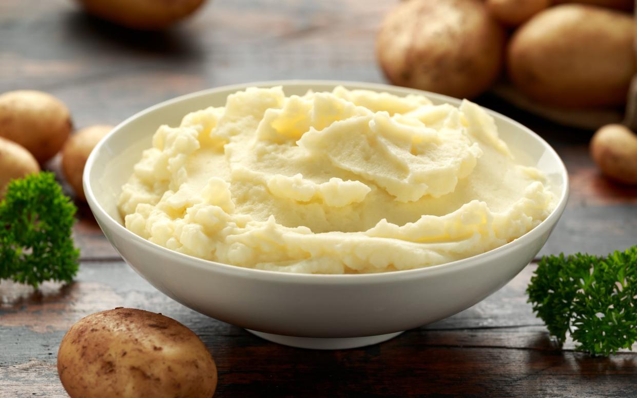 Mashed potatoes in white bowl on wooden rustic table. Healthy food.