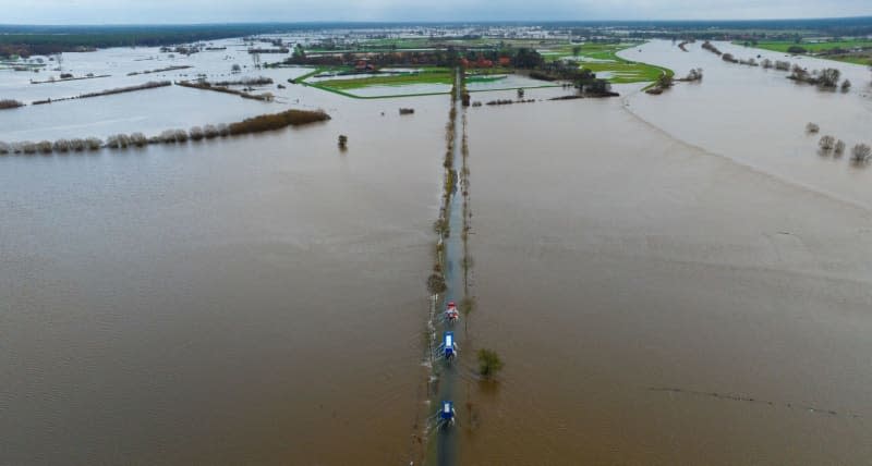 An aerial view of vehicles from the THW and the fire department drive on a partially flooded road not far from the Aller. Philipp Schulze/dpa