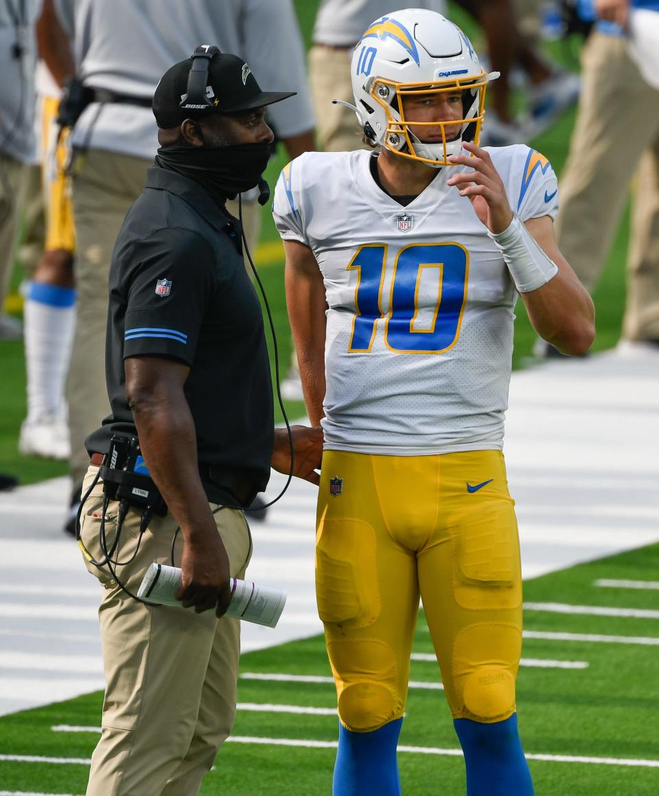 Los Angeles Chargers head coach Anthony Lynn goes over a play with quarterback Justin Herbert on Sept. 27, 2020 in Inglewood, Calif.