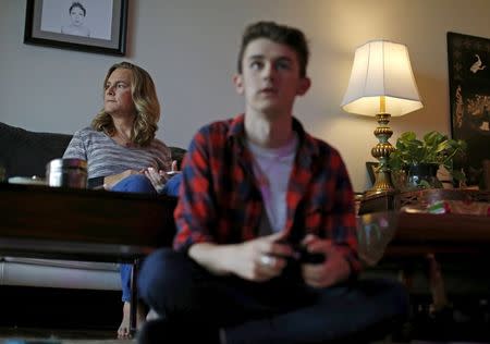 Carly Lehwald (L) looks out the window of her apartment as her son Ben plays video games in Chicago, Illinois, United States, May 30, 2015. REUTERS/Jim Young