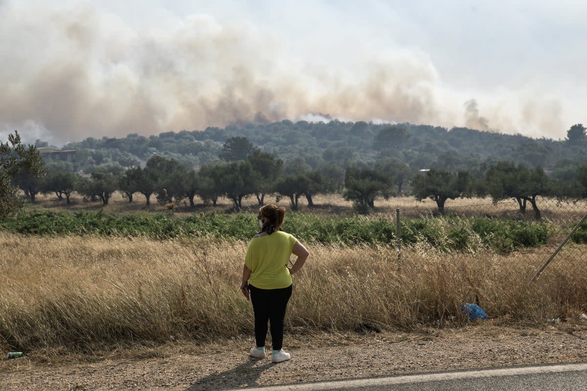 A woman looks at smoke from a wildfire some 50km southeast from the centre of Athens on July 17, 2023. (AFP via Getty Images)