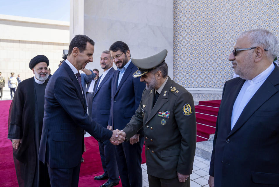 In this photo released by the official Facebook page of the Syrian Presidency, Syrian President Bashar Assad welcomes Iranian officials, followed by Iranian President Ebrahim Raisi, left, in Damascus, Syria, Wednesday, May 3, 2023. (Syrian Presidency via Facebook via AP)