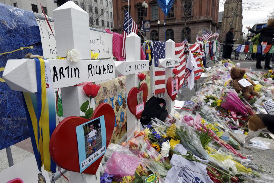 In this April 18, 2013 photo, memorials for Martin Richard, Lingzi Lu, and Krystle Campbell, killed in the bombings near the finish line of the Boston Marathon, stand among other artifacts at a makeshift memorial in Copley Square in Boston. Thousands of items from the original memorial are going on display at the Boston Public Library in April 2014 to mark the anniversary of the attacks. (AP Photo/Matt Rourke)