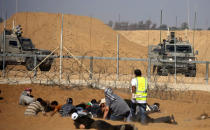 Palestinian demonstrators take cover in front of Israeli troops during a protest demanding the right to return to their homeland at the Israel-Gaza border, in the southern Gaza Strip August 17, 2018. REUTERS/Ibraheem Abu Mustafa