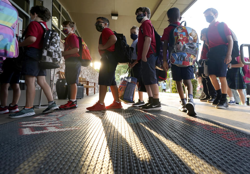 Wearing masks to prevent the spread of COVID-19, elementary school student line up to enter school for the first day of classes in Richardson, Texas, Tuesday, Aug. 17, 2021. Despite Texas Gov Greg Abbott's executive order banning mask mandates by local officials, the Richardson Independent School District and many others across the state are requiring masks for students. (AP Photo/LM Otero)
