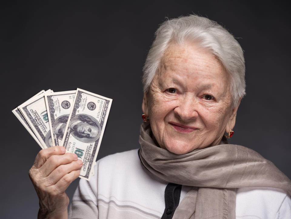 Older woman looking satisfied, holding a bunch of hundred dollar bills