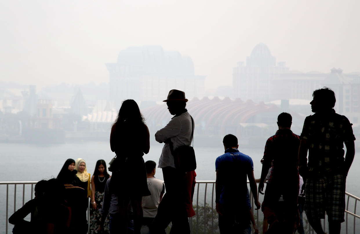 Tourists are silhouetted as they view Sentosa against the backdrop of the haze in 2015. (AP file photo)