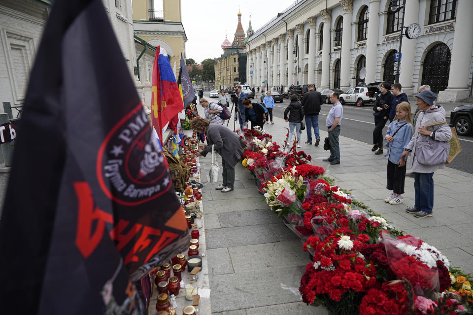 People stand next to an informal street memorial with lit candles for Wagner Group's military group members killed in a plane crash, near the Kremlin in Moscow, Russia, Tuesday, Aug. 29, 2023. Prigozhin was aboard a plane that crashed north of Moscow killing all 10 people on board. Russia's Investigative Committee said forensic and genetic testing identified all 10 bodies recovered from the crash, and the identities "conform with the manifest." (AP Photo/Alexander Zemlianichenko)