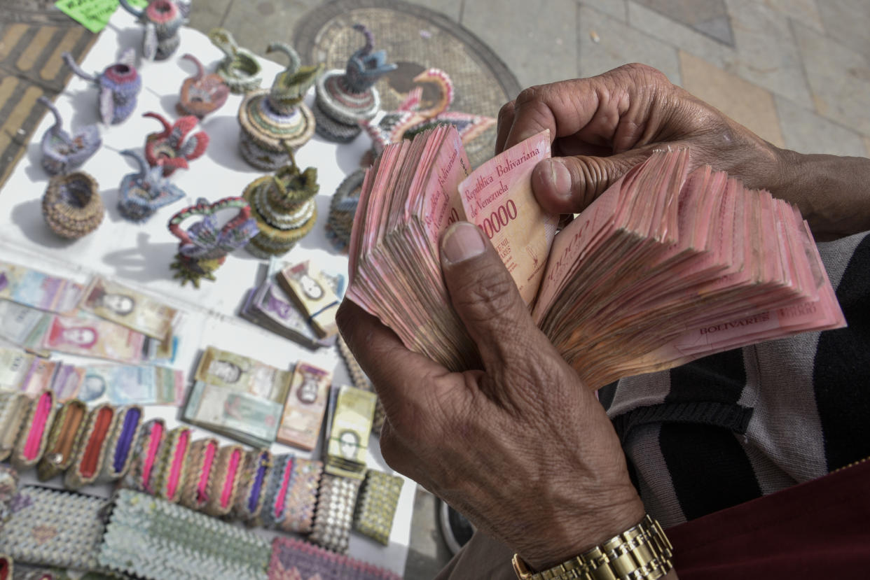 BOGOTA, COLOMBIA - MAY 18: Colombian designer Luis Orlando Ortega counts Venezuelan devalued and out of circulation banknotes Bolivares Fuertes at the main avenue of historic downtown Bogota, Colombia, on May 18, 2019. Mr. Ortega, 60 year-old, lived 43 years in Venezuela, returned to Colombia 2 years ago, escaping the economic and social crisis in Venezuela and now earns his living selling handicrafts made with the devalued Venezuelan Bolivares in the Colombian capital. Colombian and Venezuelan artists fold Venezuelan devalued banknotes into swans, baskets, model cars and purses or paint them with famous characters to offer them in the touristic area of La Candelaria. They use currencies out of circulation and also current legal banknotes of 2 and 5 Bolivares Soberanos (Sovereign Bolivar). On August 20, 2018, Venezuela changed its currency from Bolivar Fuerte (Strong Bolivar) to Sovereign Bolivar at a rate of 100,000 to 1. Due to hyperinflation, some Venezuelan banknotes are no longer found in circulation as their value decreased but remain legal tender. Cash is worth so little that banknotes are often burnt or thrown away. According to the World Economic Outlook report released by International Monetary Found on April 2019, Venezuela is expected to suffer this year a 10 million percent inflation raise, making it the most miserable economy in the world. As a consequence, some banknotes turned almost obsolete. (Photo by Guillermo Legaria/Getty Images)