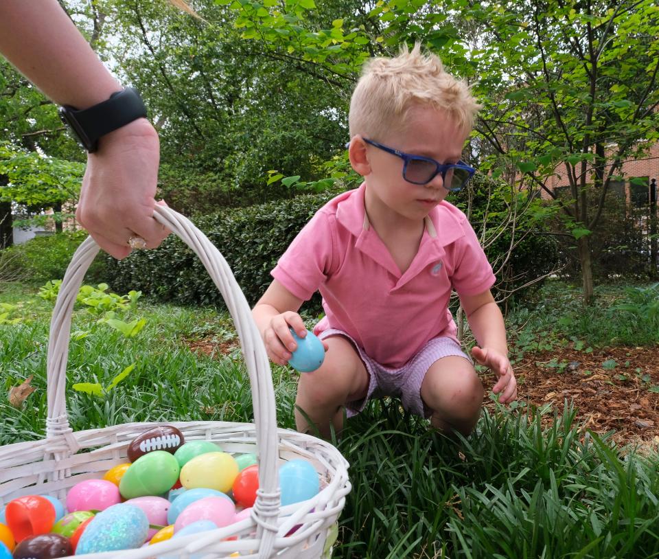 Liam Mitchell finds eggs in the monkey grass at the Panhellenic Association's annual Easter egg hunt on the lawn of the President's Mansion on the campus of the University of Alabama on April 2, 2023.