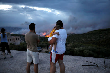 A man hugs his son as he watches a wildfire raging in the town of Rafina, near Athens, Greece, July 23, 2018. REUTERS/Alkis Konstantinidis