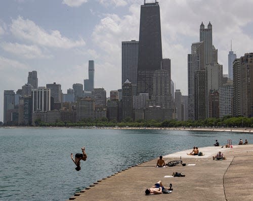 A man leaps into Lake Michigan along the lakefront near Oak Street Beach while sunbathers soak up temperatures in the 90s on Wednesday, June 15, 2022, in Chicago.