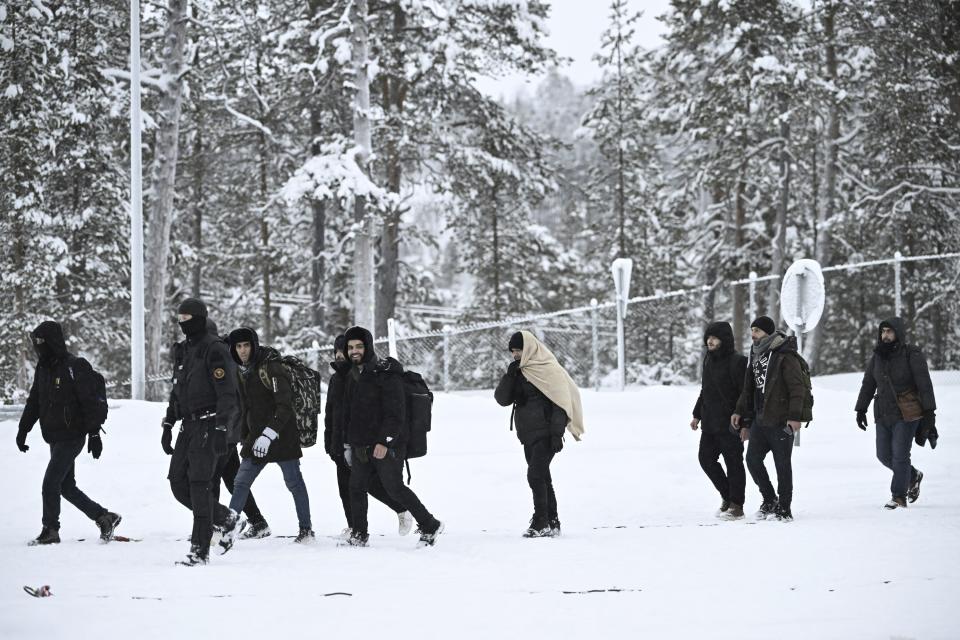 Finnish Border Guards escort migrants arriving at the Raja-Jooseppi international border crossing station between Russia and Finland, in Inari, northern Finland, Saturday, Nov. 25, 2023. The European Union’s border agency says that it will send dozens of officers and equipment as reinforcements to Finland to help police its borders amid suspicion that Russia is behind an influx of migrants arriving to the country. (Emmi Korhonen/Lehtikuva via AP)