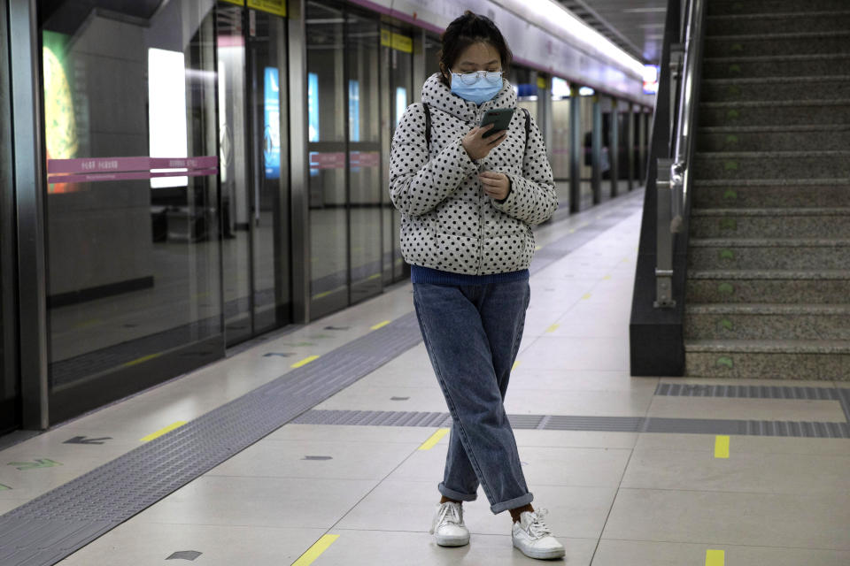 In this April 1, 2020, photo, a woman waits for her train at a subway station after entering with a green pass in Wuhan in central China's Hubei province. Life in China post-coronavirus outbreak is ruled by a green symbol on a smartphone screen. Green signifies the "health code" that says the user is symptom-free. It is required to board a subway, check into a hotel or enter Wuhan, the city where the global pandemic began. (AP Photo/Ng Han Guan)