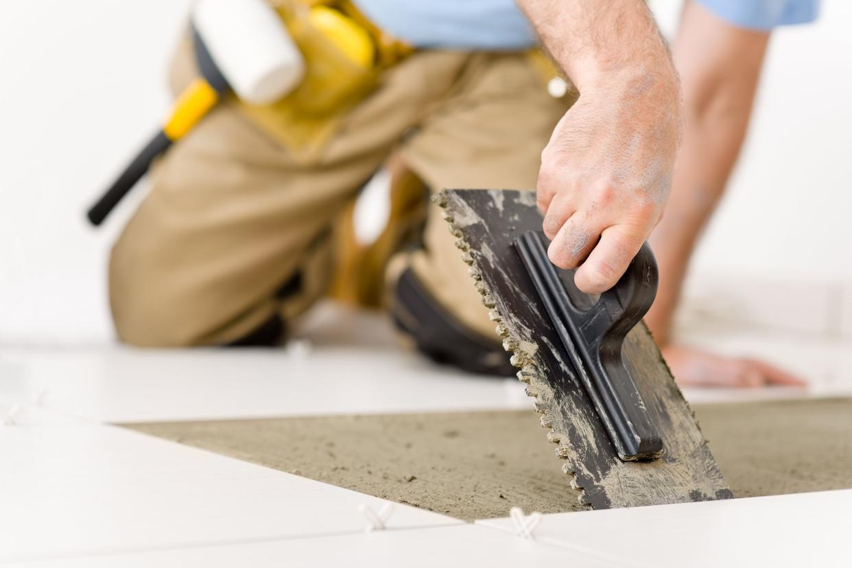 man laying tile, trowel with mortar