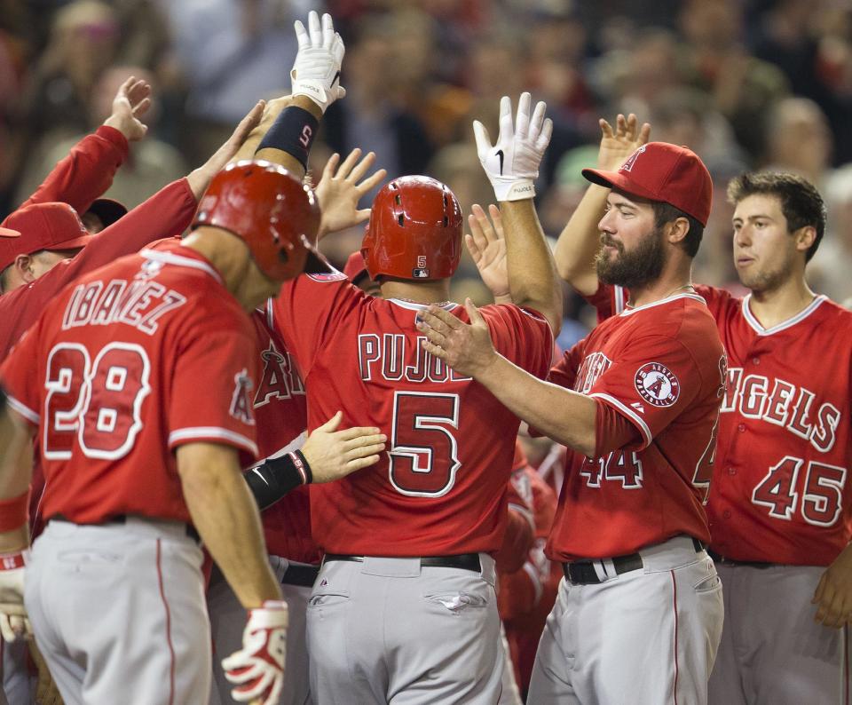 Los Angeles Angels Albert Pujols (5) is greeted his teammates at home plate after hitting a two-run homer against Washington Nationals Taylor Jordan in the fifth inning of a baseball game in Washington, Tuesday, April 22, 2014. This was Pujols 500th career home run. (AP Photo/Pablo Martinez Monsivais)