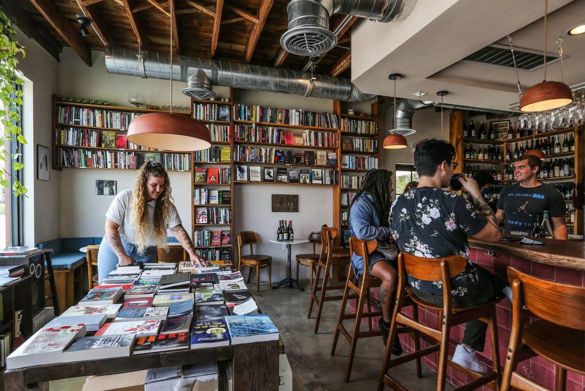 Audrey Wright unpacks books as Sef Chesson, Ben Yen and Brian Wright drink coffee at Paradis Books & Bread in North Miami. Along with Bianca Sanon, they’re co-owners of the wine bar and book shop.