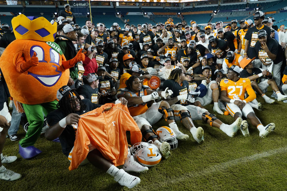 Tennessee coach Josh Heupel, center, in white, poses with the team and the Orange Bowl mascot after the team's win over Clemson in the Orange Bowl NCAA college football game, early Saturday, Dec. 31, 2022, in Miami Gardens, Fla. Tennessee won 31-14. (AP Photo/Lynne Sladky)
