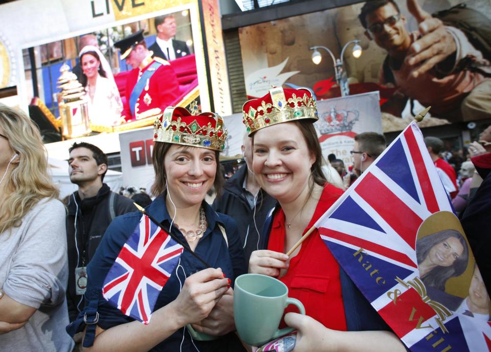 FILE - Molly Davis, left, and Amanda D'Aquila join a large crowd in New York's Times Square to watch the royal wedding, April 29, 2011. The pomp, the glamour, the conflicts, the characters — when it comes to the United Kingdom’s royal family, the Americans can’t seem to get enough. (AP Photo/Mark Lennihan, File)