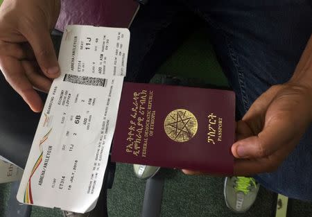 A passenger displays an Ethiopian passport and an Ethiopian Airlines boarding pass as he sits inside ET314 flight to Eritrea's capital Asmara at the Bole International Airport in Addis Ababa, Ethiopia July 18, 2018. REUTERS/Tiksa Negeri