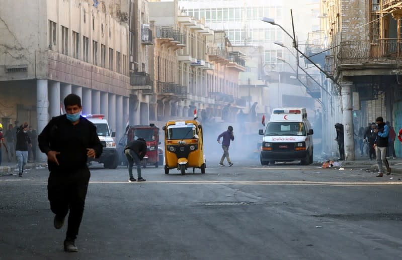 Iraqi demonstrators run from tear gas during the ongoing anti-government protests in Baghdad