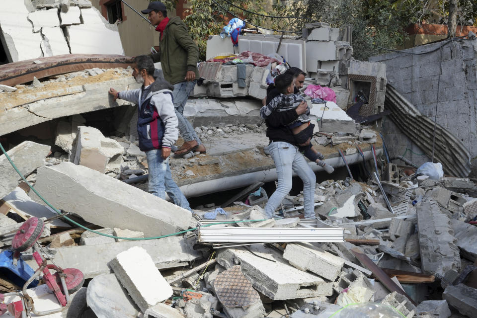 Palestinians evacuate a child from the rubble of the Darwesh family building destroyed in an Israeli airstrike in Nusseirat refugee camp, central Gaza Strip, Tuesday, Jan. 2, 2024. (AP Photo/Adel Hana)