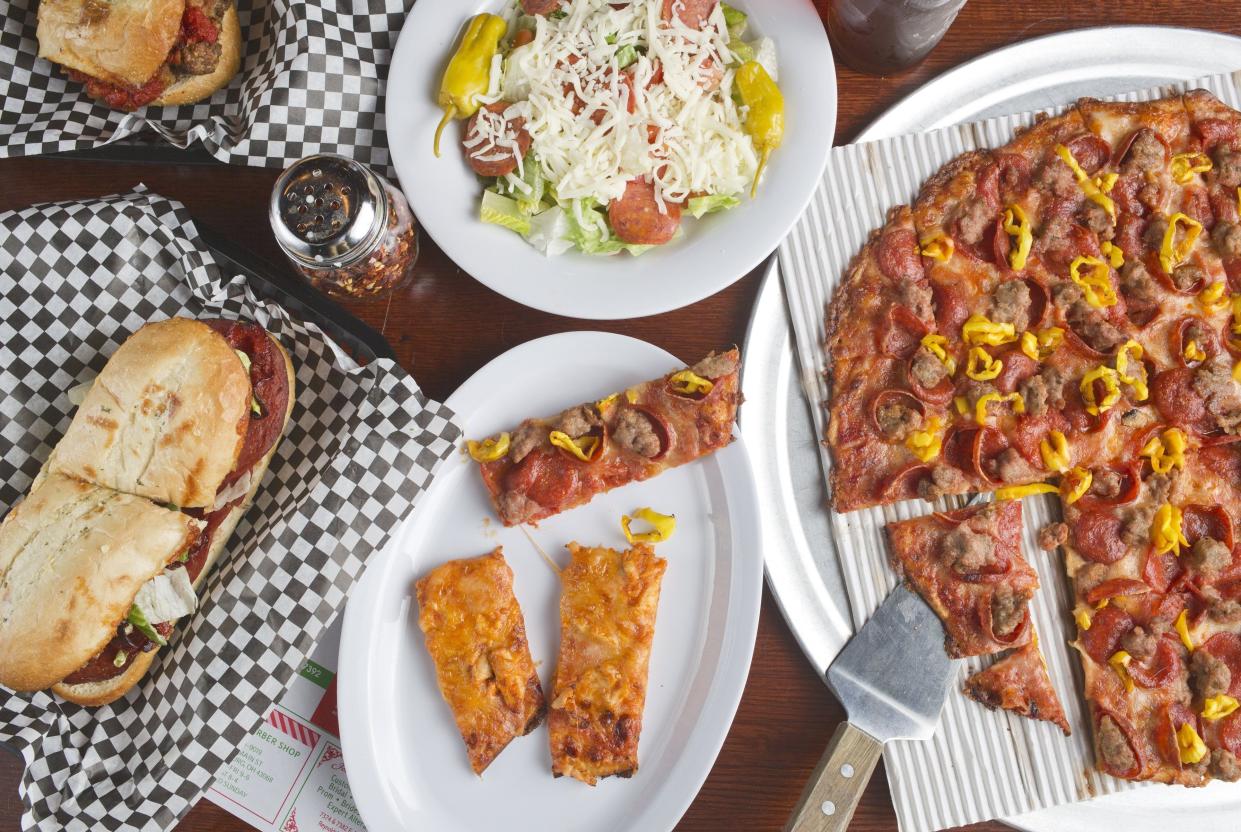 Clockwise from left: an Italian sub, a meatball sub, a side salad and a large pizza with pepperoni, sausage and banana peppers, plus two slices of the Buffalo chicken pizza at Vick's Gourmet Pizzeria