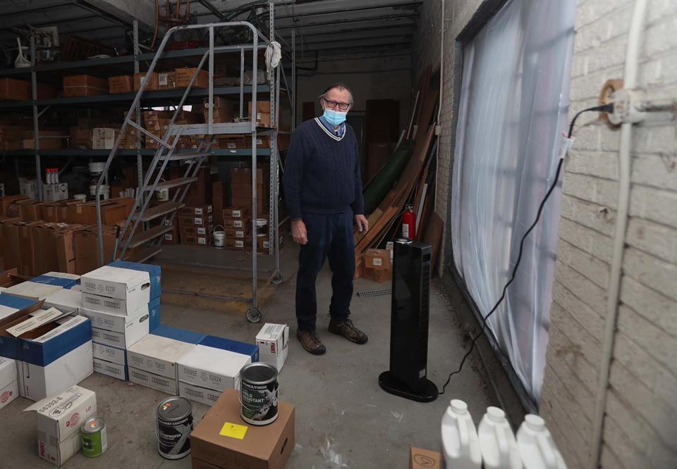 Phil January stands next to a space heater in the storage area of his family's business at January Paint & Wallpaper on Monday. The heat has been out in the store since Saturday because of water in gas lines but the store has been kept open and the paint has been kept from freezing with the use of space heaters.