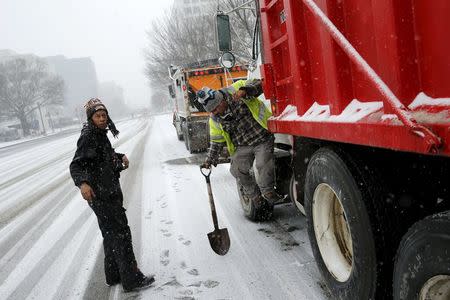 Crew members work on salt trucks as the snow begins to fall in Washington January 22, 2016. REUTERS/Jonathan Ernst