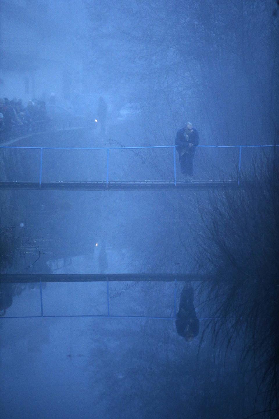 Man stands on a bridge over Tundzha river as he waits for the start of the Epiphany Day celebration in the town of Kalofer