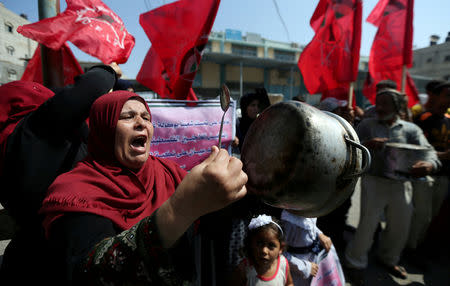 FILE PHOTO: A Palestinian woman holds a cooking pot during a protest against a U.S. decision to cut funding to the United Nations Relief and Works Agency (UNRWA), outside an aid distribution center, in Khan Younis in the southern Gaza Strip September 4, 2018. REUTERS/Ibraheem Abu Mustafa/File Photo