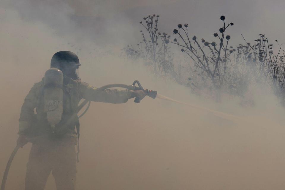 The cross-border clashes between Israel and Hezbollah have forced tens of thousands of Israelis from their homes. Here, an Israeli firefighter douses a blaze started by a downed drone launched from southern Lebanon.