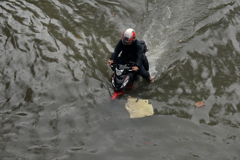 A motorcyclist tries to ride along a flooded street in Manila on August 19, 2013. At least three people have died in the Philippines after torrential rain engulfed parts of the main island of Luzon including Manila where neck-deep water swept through homes forcing thousands into emergency shelters