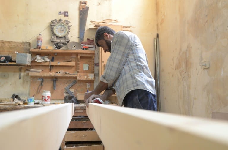 A Syrian furniture worker measures wood at Yussef al-Qabuni's workshop